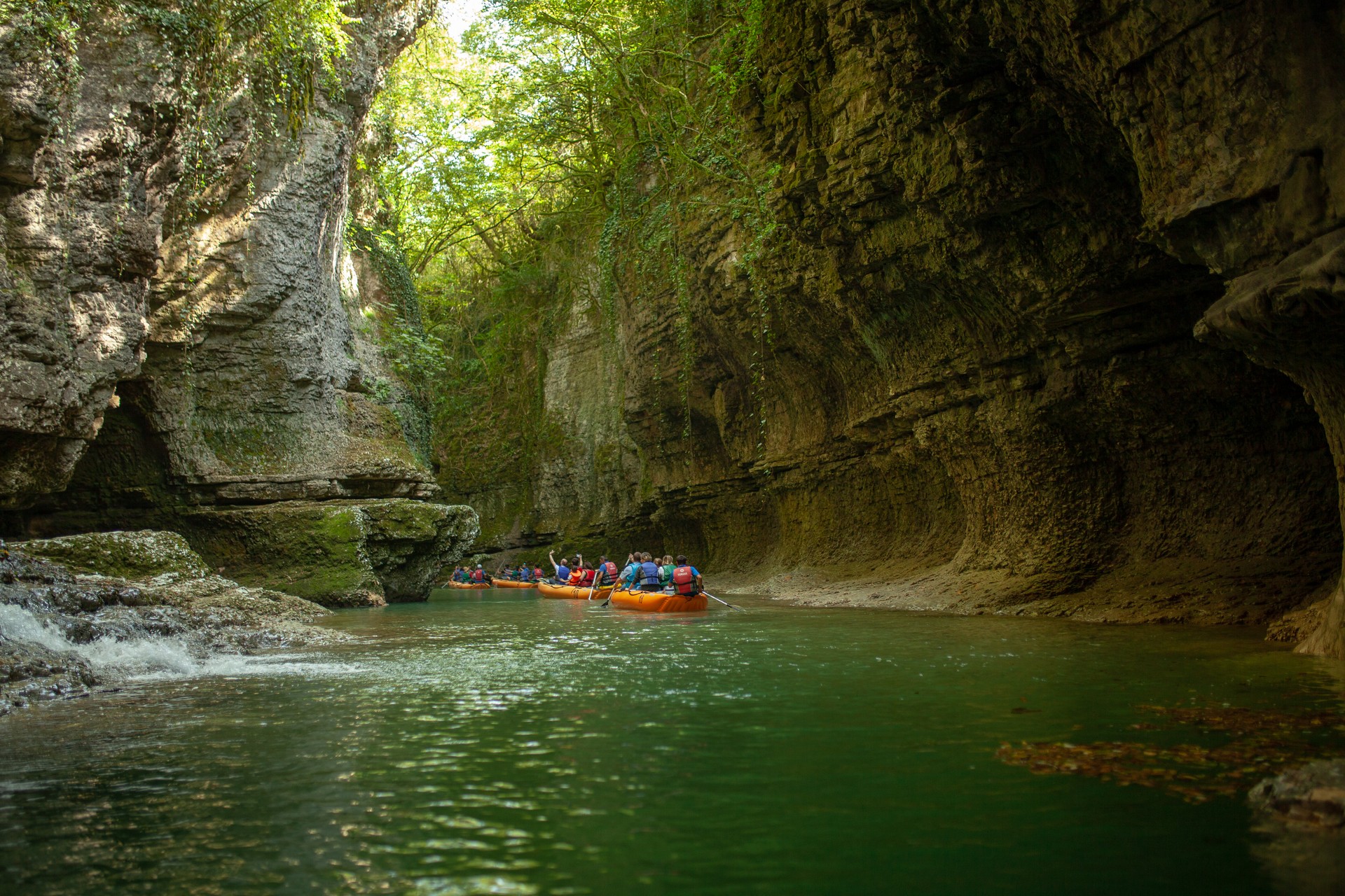 People on an excursion between rocks in inflatable boats along the canyon