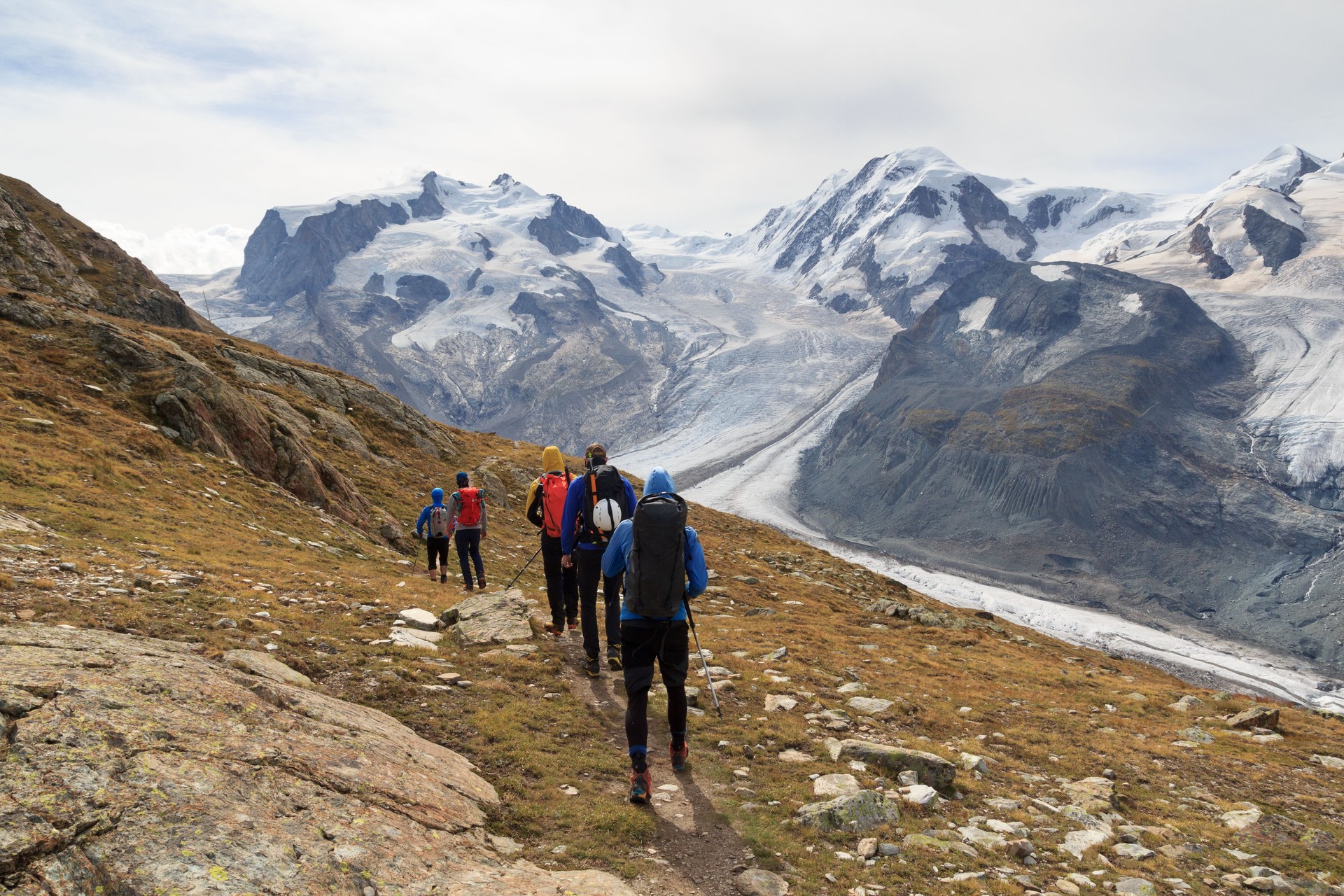 Panorama view with mountain Dufourspitze (left), Gorner Glacier, mountain Lyskamm (right) and group of mountaineers hiking towards mountain massif Monte Rosa in Pennine Alps, Switzerland