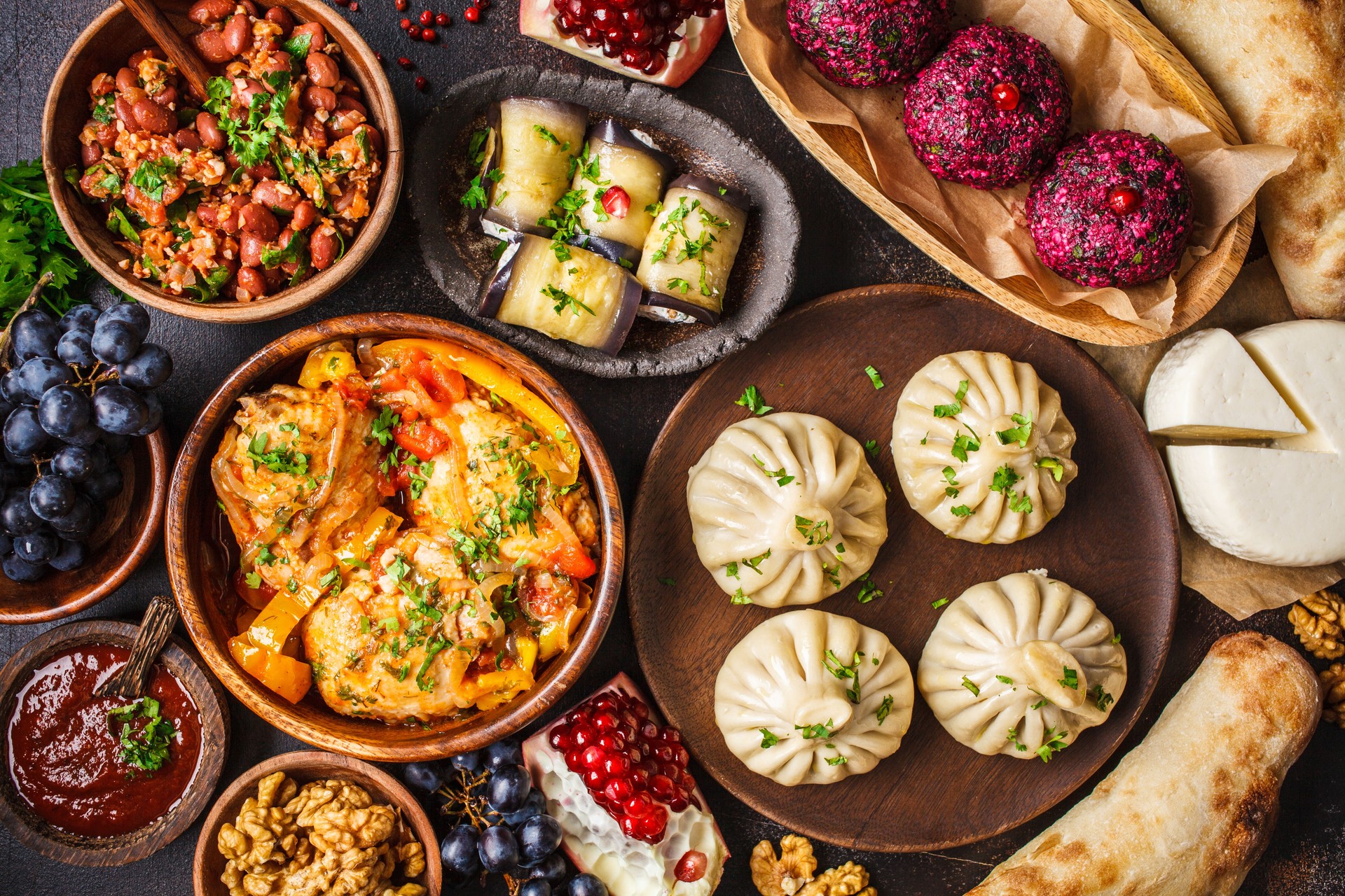 Traditional Georgian cuisine background. Khinkali, phali, chahokhbili, lobio, cheese, eggplant rolls, dark background.