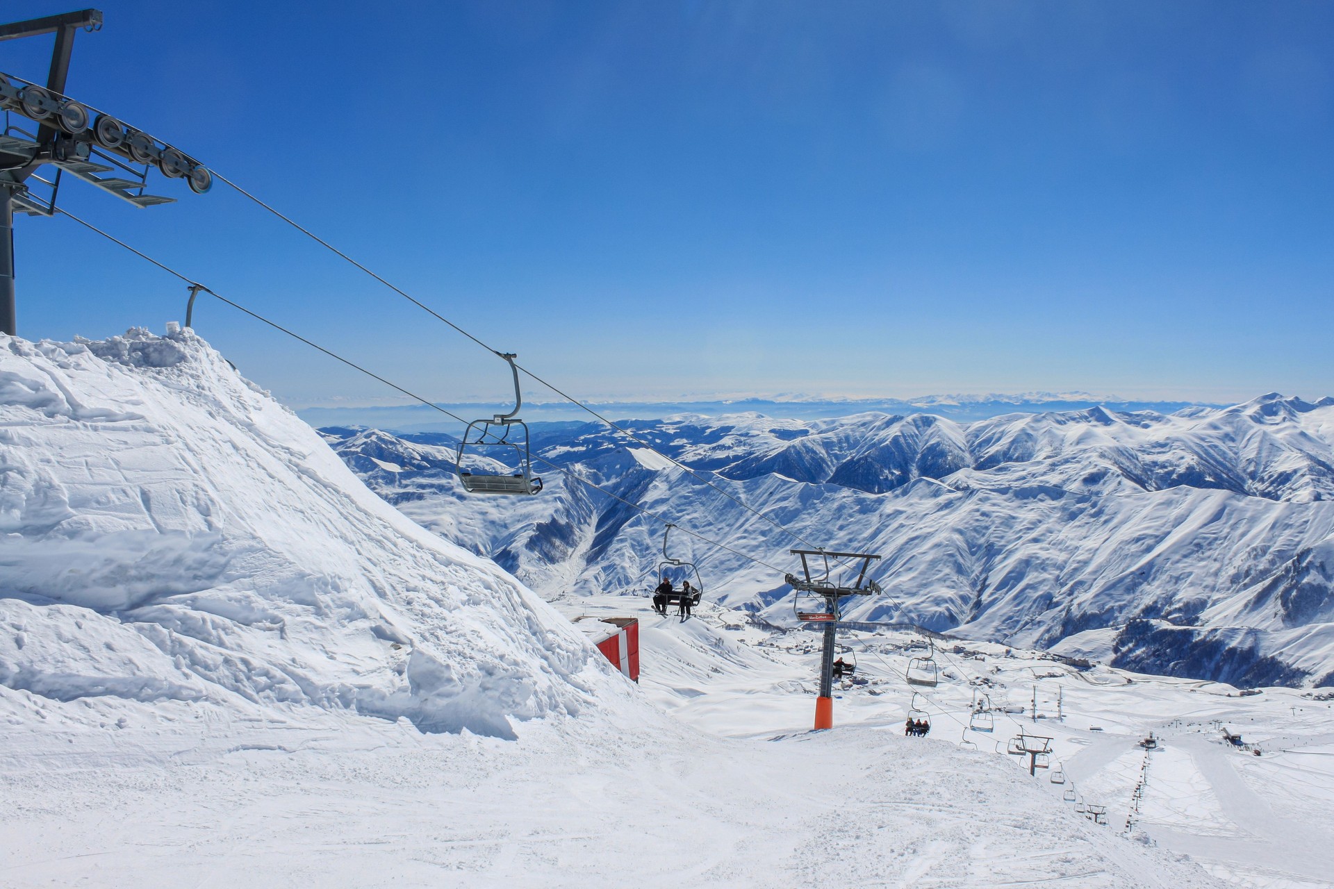 Chairlift on the background of snow-capped peaks and blue sky