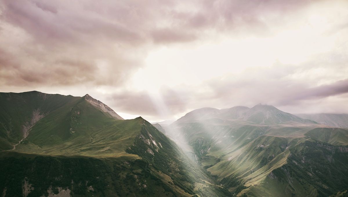 the sun's rays pass through the clouds. Caucasian Mountain in summer. Cross Pass in Georgia. Gudauri District. Source of Aragvi River. 