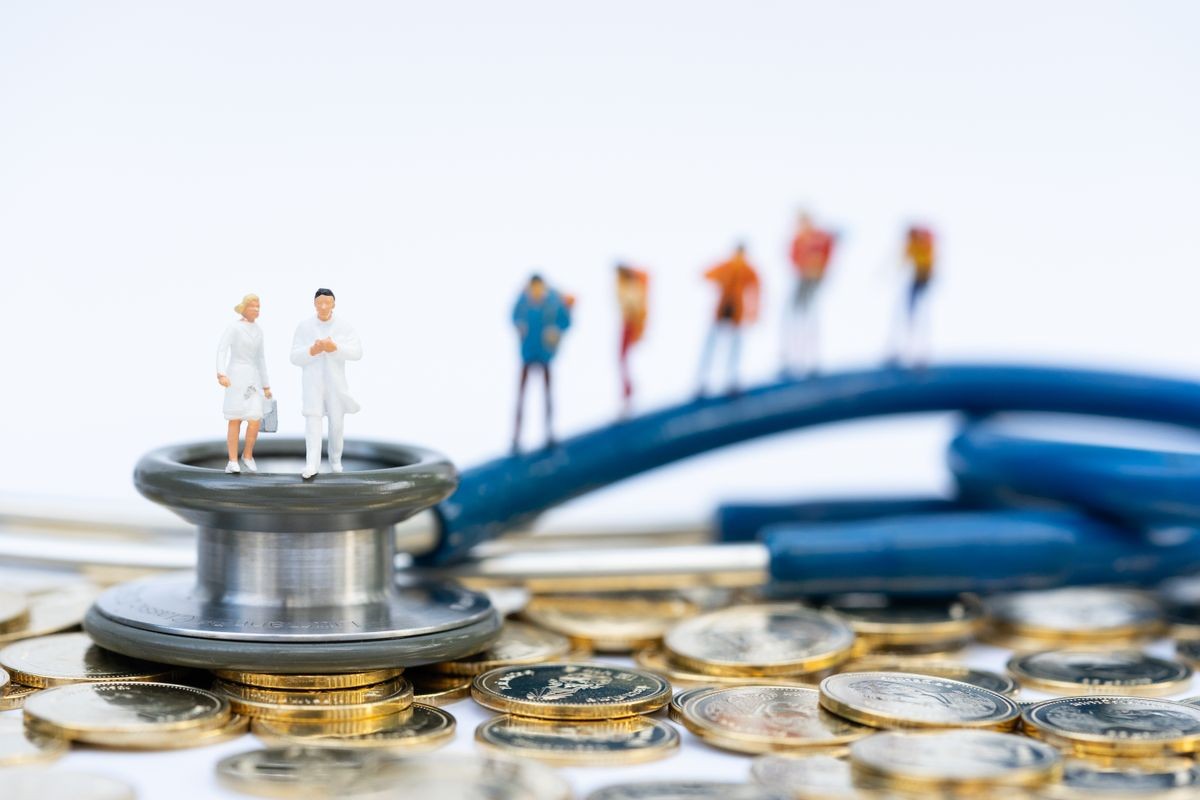 Miniature people, emergency medical team on stethoscope with travelers as backdrop. Health care and life insurance concept.