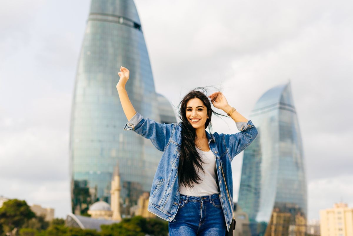 attractive young brunette girl laughing, posing against a background of modern buildings in the city of Baku